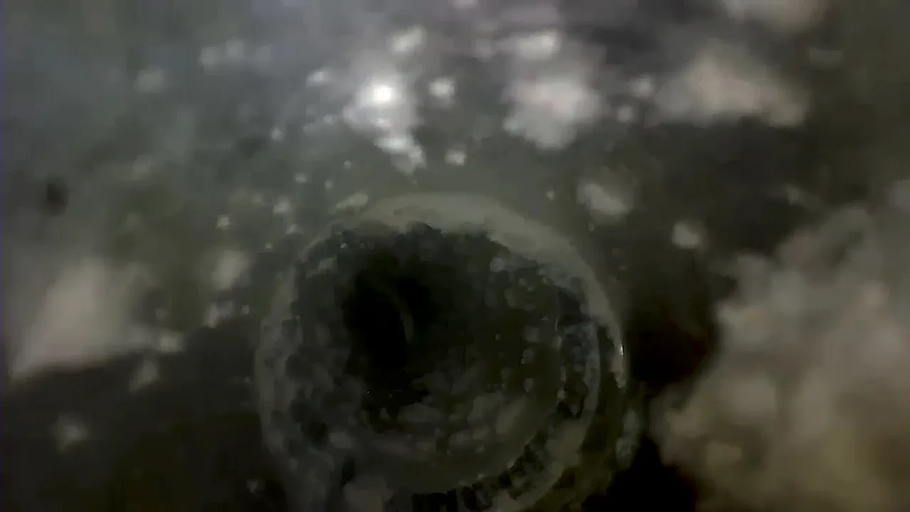 Inspection camera view of a circular air duct nearly restricted by debris